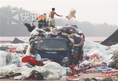 房山窦店镇的废旧衣服集散地,工人们从车上卸下大量废旧衣服和被褥。
